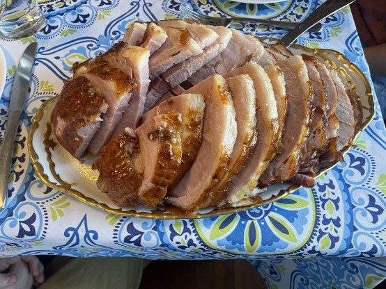 A half of a ham is fresh out of the oven sliced and juicy on a gold edged plate