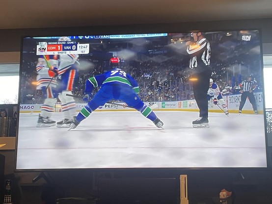 Attack player has his back to the camera leaned over into the face of circle on a large TV