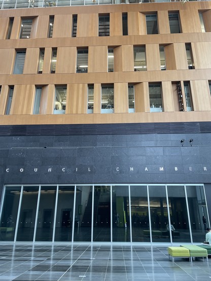A dramatic black stone facade with tall floor level windows mark the entrance. The floors above are a brown slate and the windows are irregular shaped rectangles.