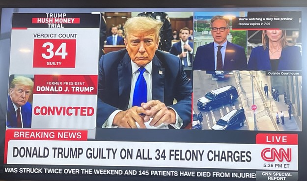 A picture of a television screen showing Trump in the middle at his table in the court room. On the left side is 34. Guilty. Convicted. On the right is a live shot of street street