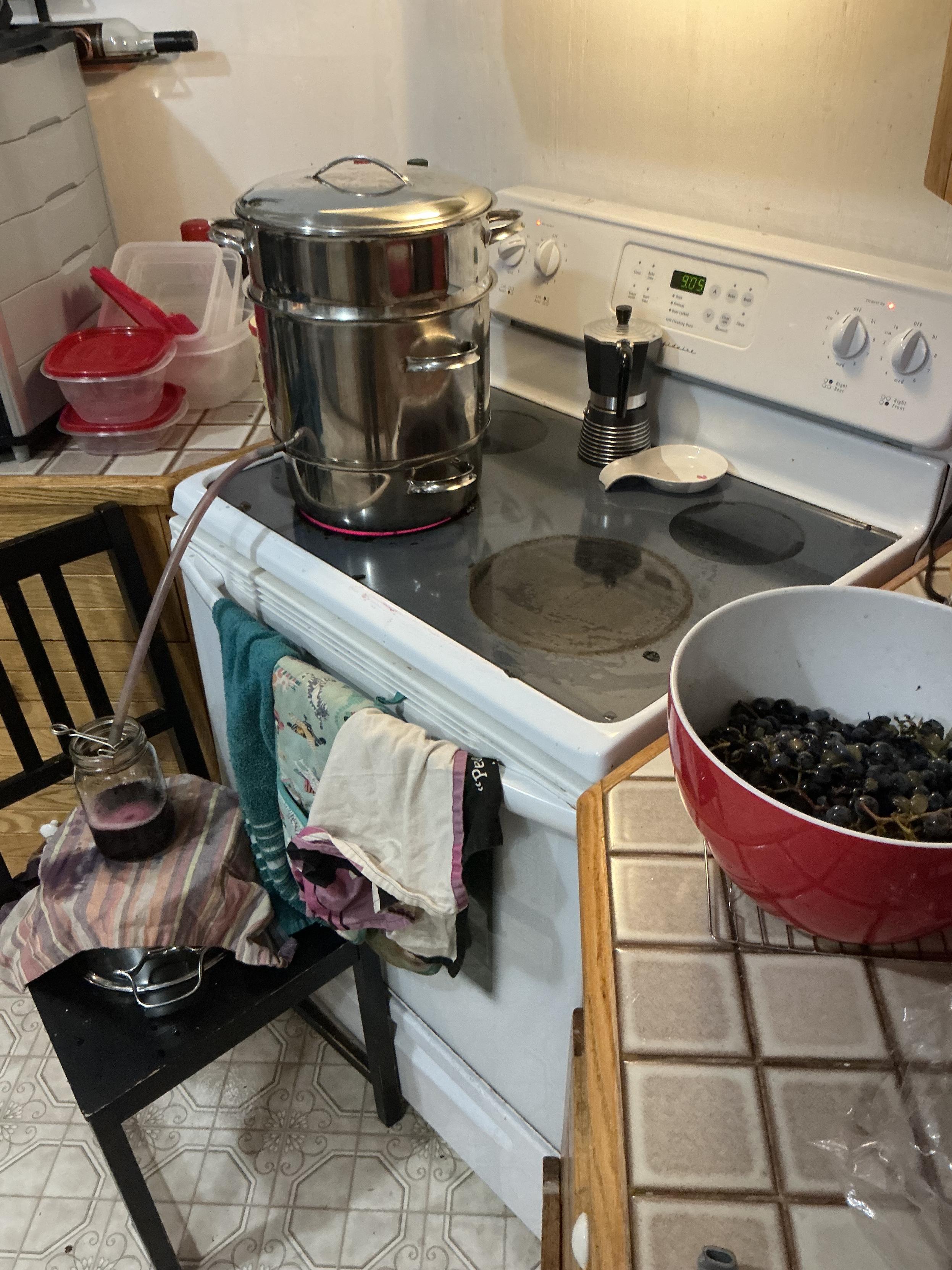 Looking at the set up on the stove as process continues, there’s one jar sitting one through four on chair below the stove, which has the three level boiler sitting on top and a bowl of fresh grapes ready to be added