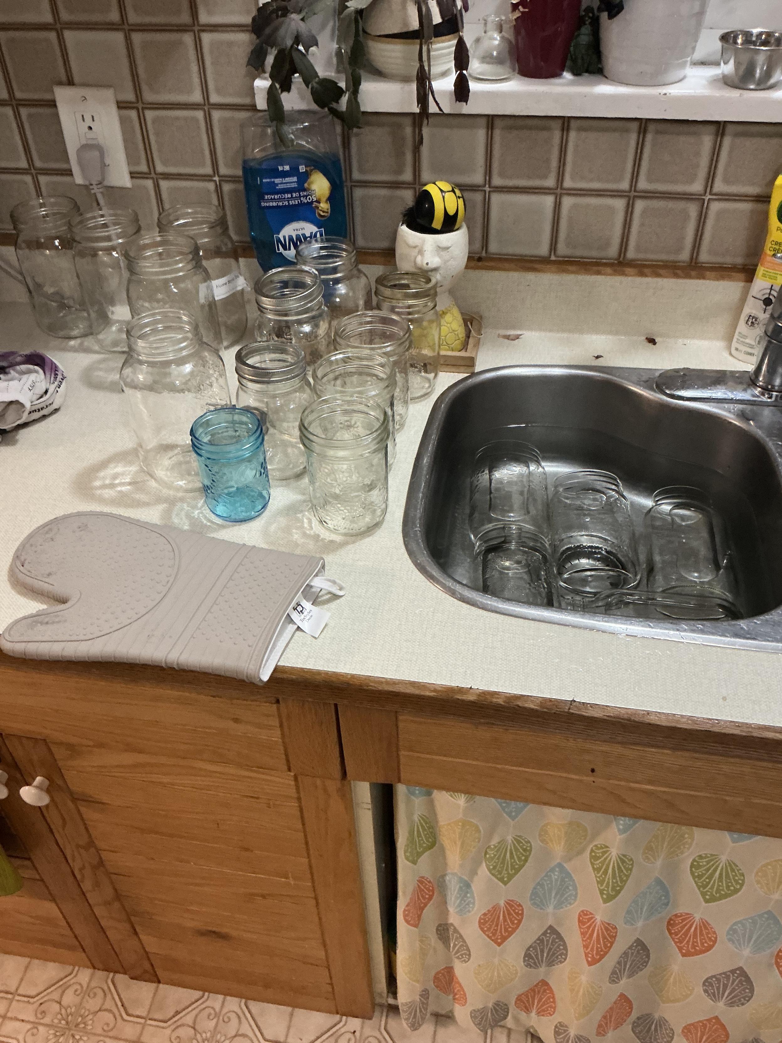 New clean jars are sitting on the counter and soaking in hot water in the sink waiting their turn