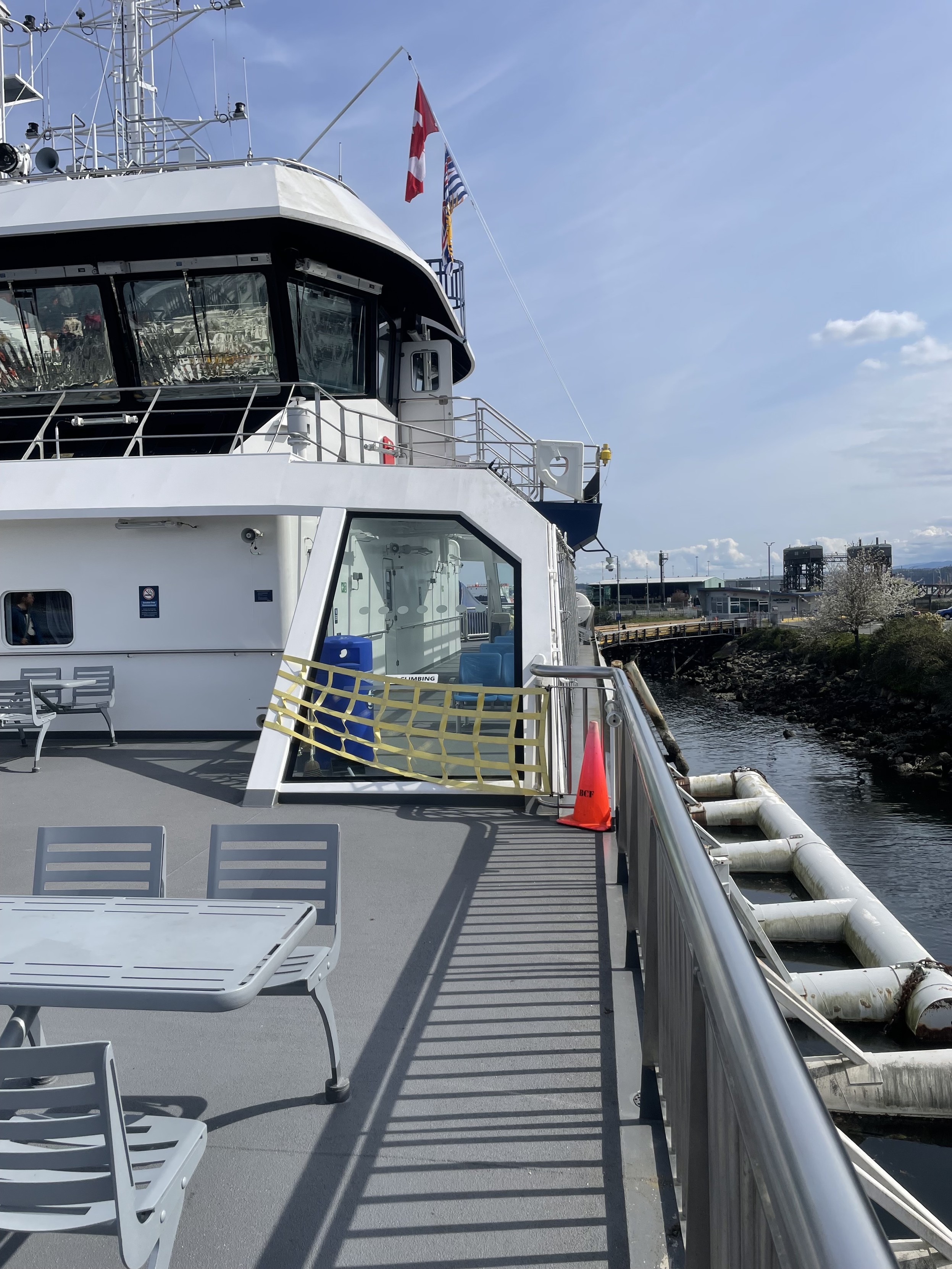 along the passenger deck of the shop some chairs and table and the looming glass of the bridge
